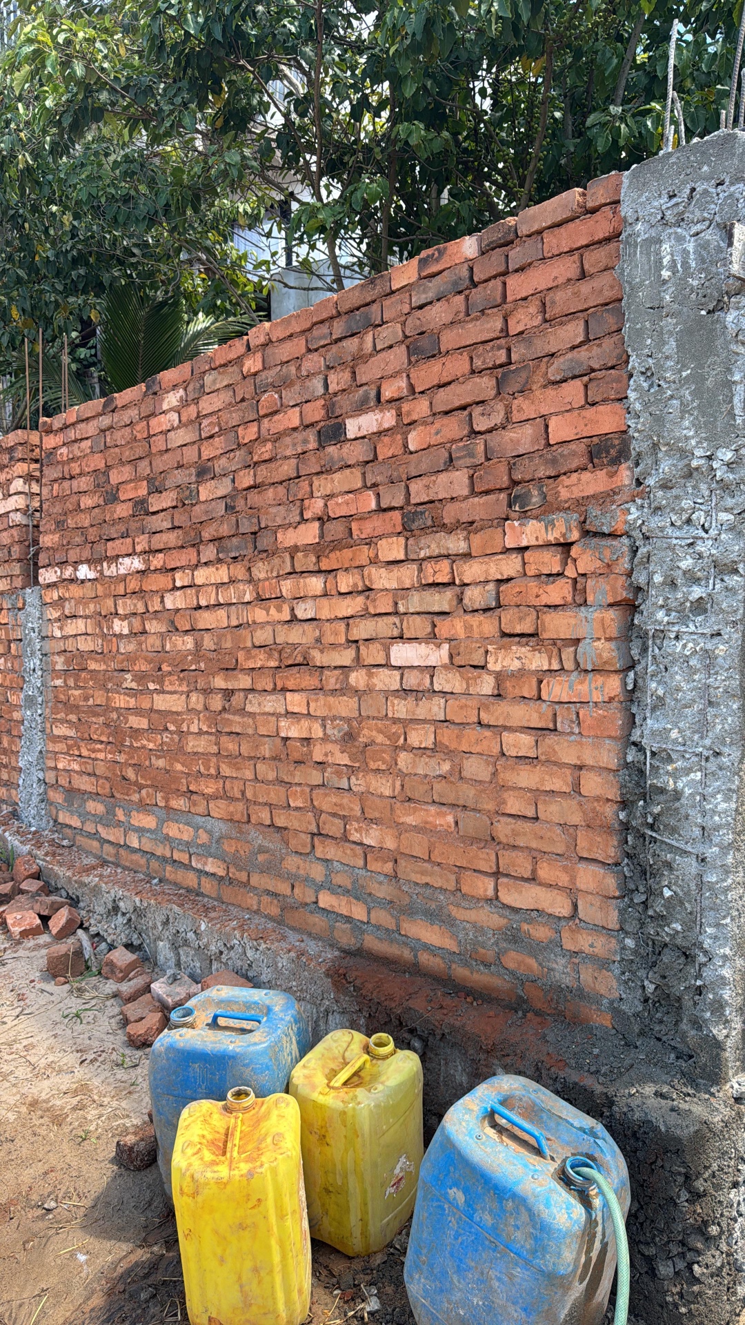 Mur de clôture en briques rouges sur soubassement béton